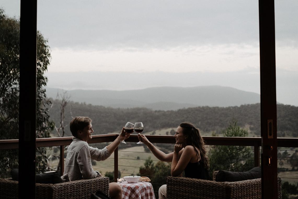 A couple sitting on the balcony at Kangaroo Ridge Retreat toasting to the view and eating dinner together