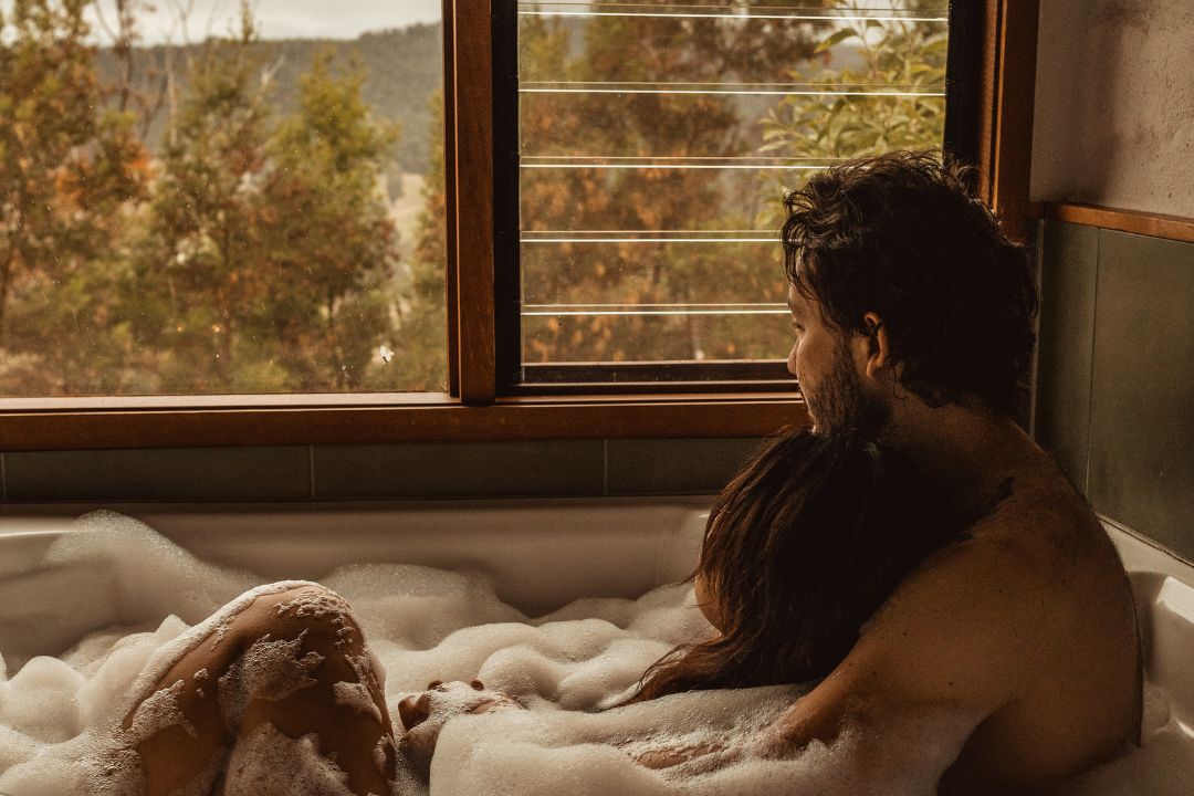 A couple sitting in a bath looking at the mountains in the background