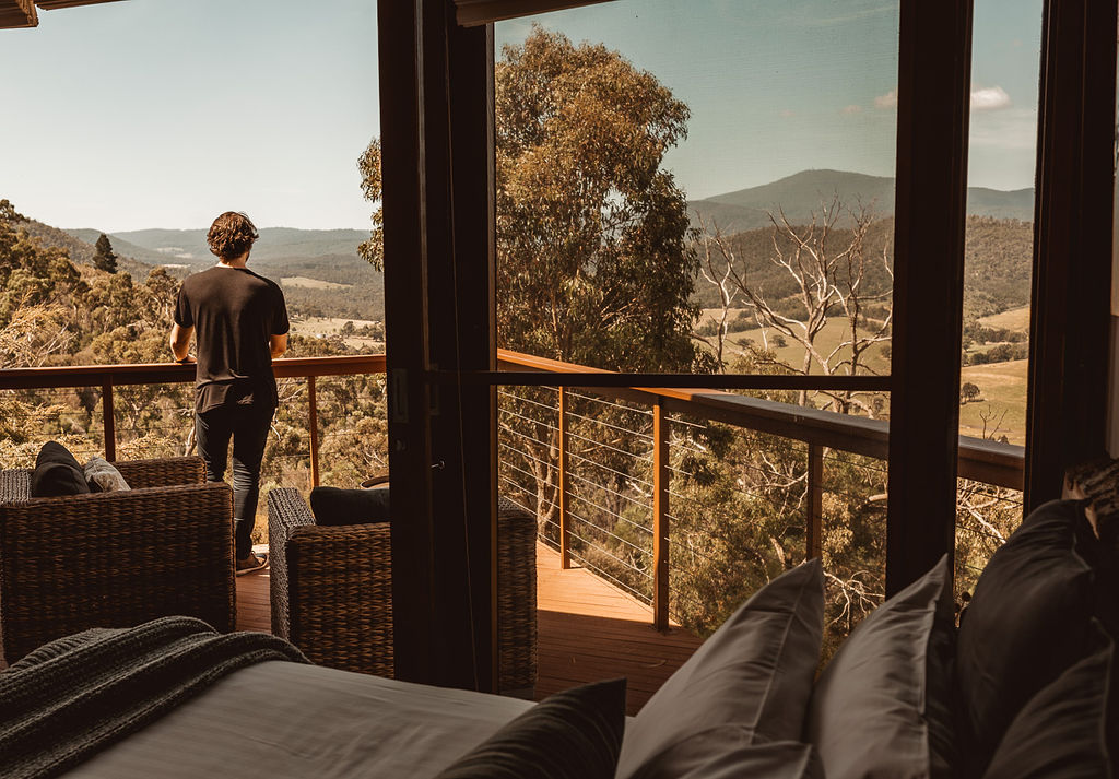 A man looking out at the view of the Mountains from a balcony