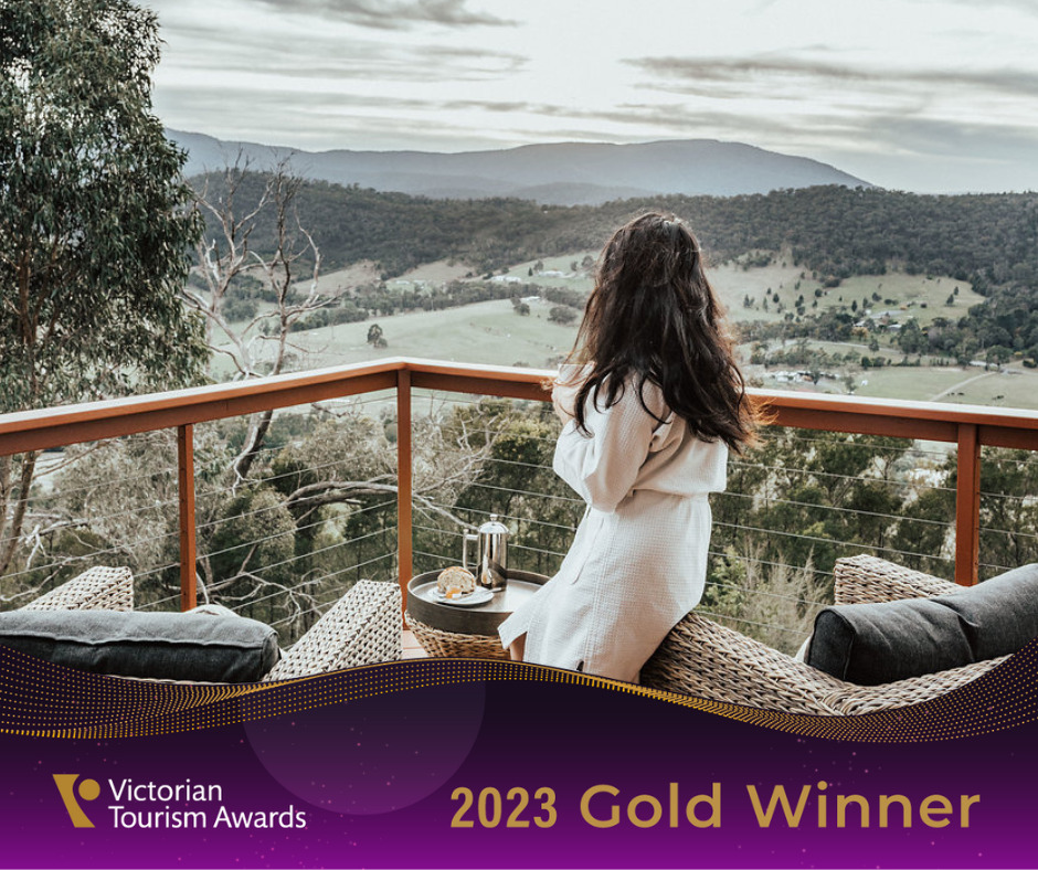 A women sitting on a balcony while having breakfast looking at the mountain views with the VTIC Gold winner banner in the foreground.